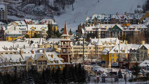 Aerial view of snow-covered roofs and the clock tower in Tremblant’s pedestrian village during winter.