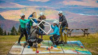 A group participating in an outdoor team-building activity at the Tremblant summit with mountains in the background.
