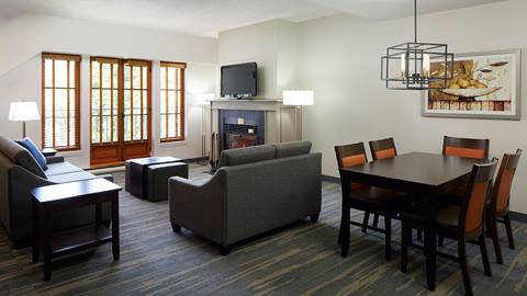 spacious multi-room suite at Homewood Suites by Hilton in Mont-Tremblant featuring a dining area, living room with fireplace, and large windows.