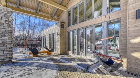 Modern entrance of the Verbier vacation rental at Tremblant Resort featuring a stone-pillar patio and large glass windows in winter.