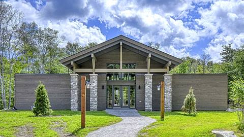 Exterior view of the modern Verbier vacation rental pavilion at Tremblant with stone pillars and wood siding during summer.