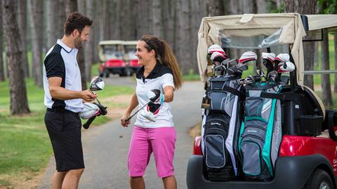 smiling golfers selecting gear beside a cart at tremblant resort, highlighting convenient golf club rentals for an easy day on the course