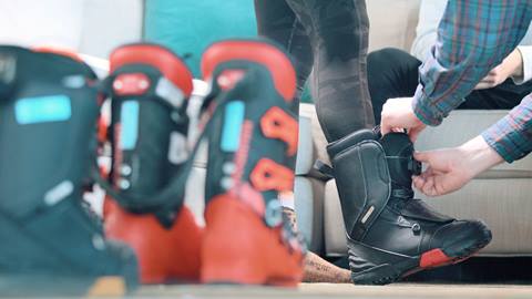 close-up of a professional technician fitting a guest with snowboard boots 