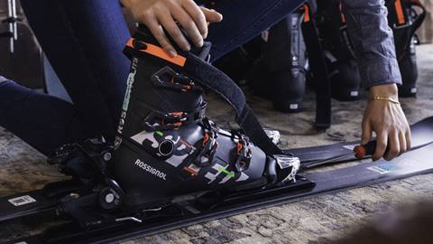 Close-up of a Rossignol ski boot being fitted into a ski binding by a technician inside a Mont-Tremblant vacation rental.