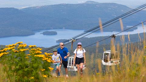 family hiking along alpine trails under the gondola at mont tremblant resort with lake views in the background