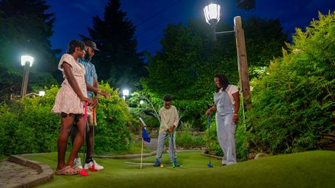 family enjoying a sunny day playing mini golf at le petit géant course at mont tremblant resort