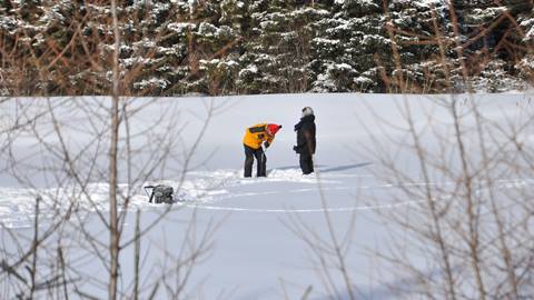 Wilderness guide in snowy forest teaching how to build a snare trap for food foraging during a survival class in Tremblant