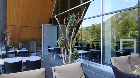 Modern outdoor patio at Altitude restaurant in Mont-Tremblant featuring dining tables, lounge seating, and glass railings overlooking the mountain.