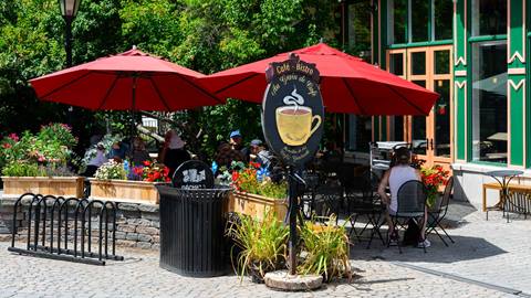 Enseigne extérieure et parasol rouge du bistro Au Grain de Café dans le village piétonnier de Mont-Tremblant.