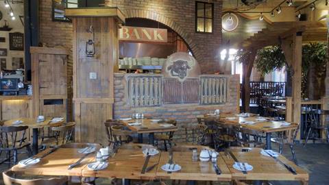 Rustic interior of Bullseye Saloon & Grillades restaurant at Mont-Tremblant featuring wooden tables, brick arches, and western-themed decor.