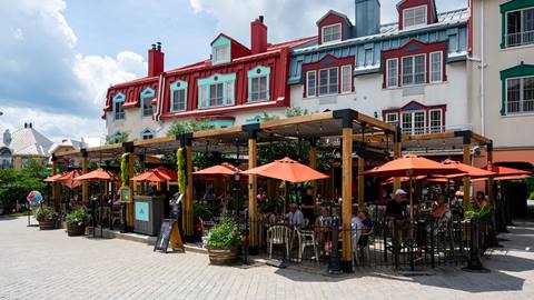 Vue extérieure de la terrasse du restaurant Fat Mardi’s à Mont-Tremblant, avec parasols rouges et places assises dans le village piétonnier.