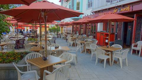 Exterior view of the Fat Mardi’s restaurant patio at Mont-Tremblant featuring red umbrellas and outdoor seating in the pedestrian village.
