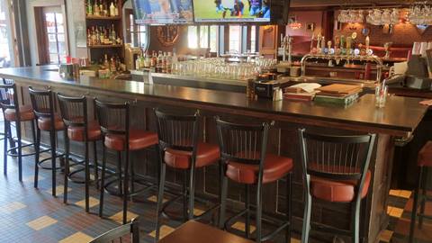 Interior view of the bar at Fat Mardi’s restaurant in Mont-Tremblant featuring a long wooden counter, bar stools, and televisions.